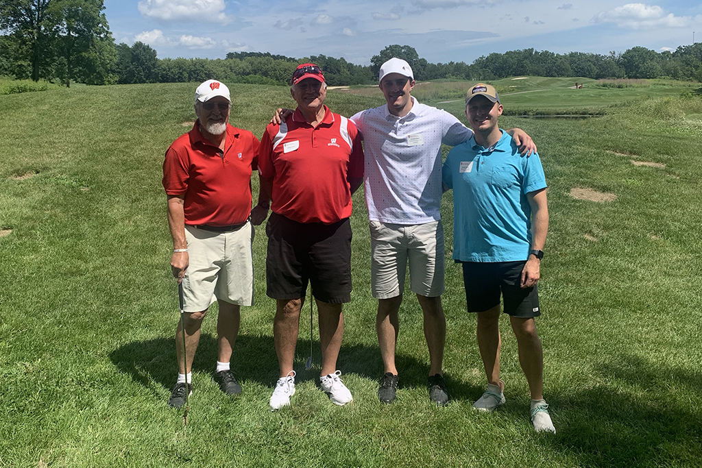 A group of alumni smile at the 2022 golf outing, outside in the sun