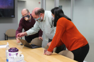 Aaron Gilson, Jay Ford, and Arveen Kaur looking at a computer screen.