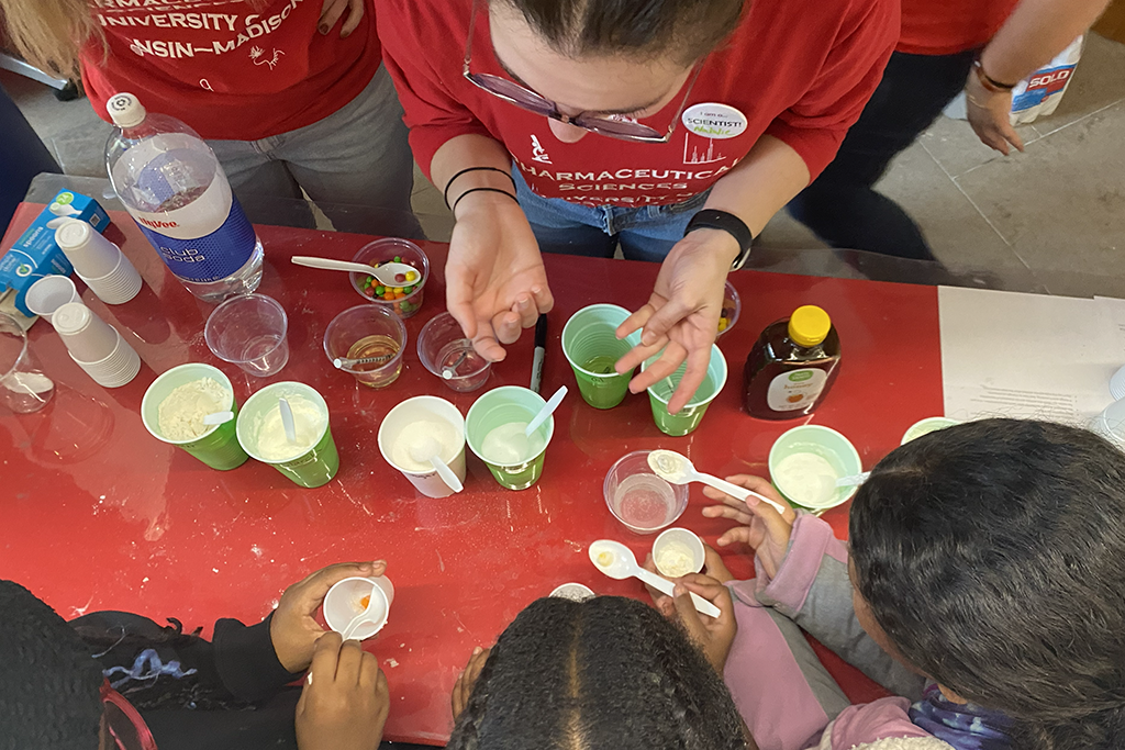 Young kids look over a table with green paper cups