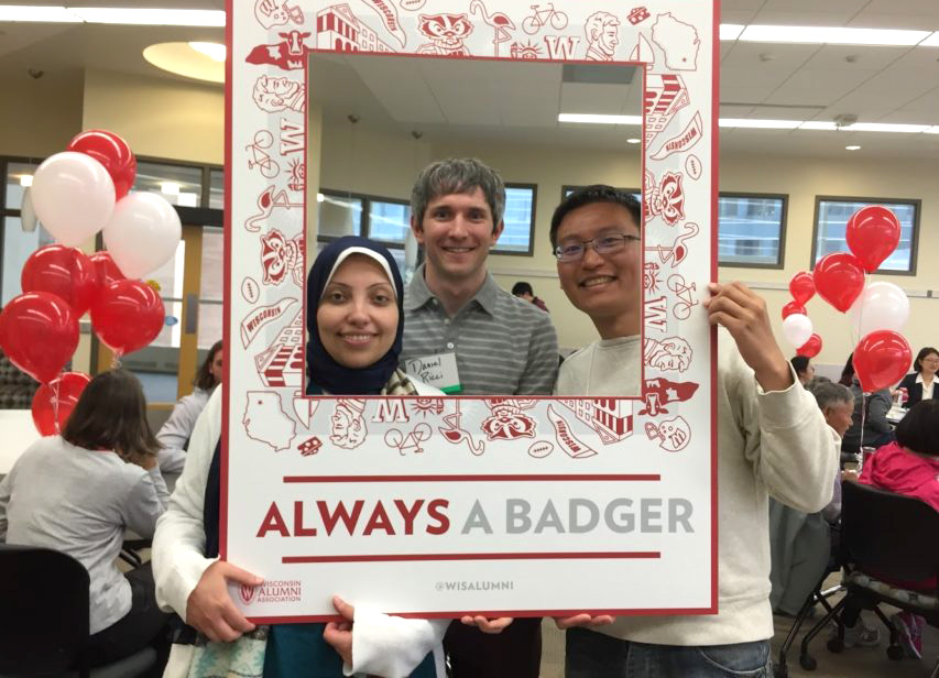 Three students from diverse backgrounds pose together inside a frame labeled "Always a Badger"
