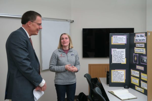 Samantha Lewiston explaining her informational board about the Rho Chi Society to Provost Karl Scholz