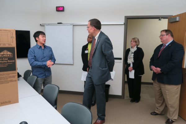 Kong Vang speaking to Provost Karl Scholz while Cierra Brewer and Dean Steve Swanson listen on the side
