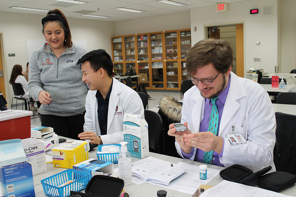 Marina Maes teaches two PharmD students about blood glucose monitors