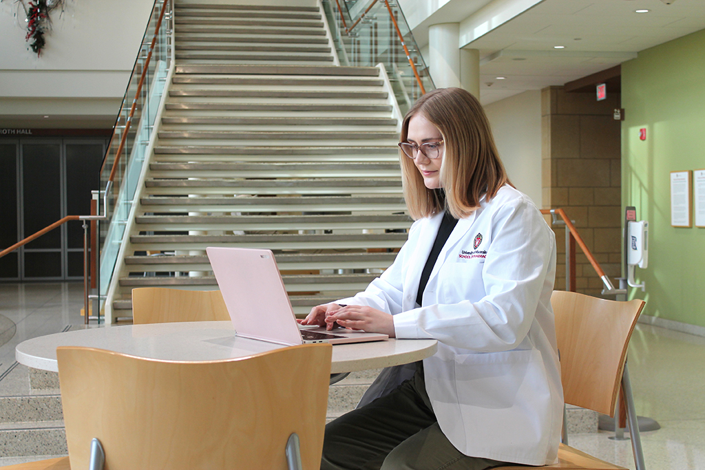Morgan Oettinger, in her white coat, works at her computer. 