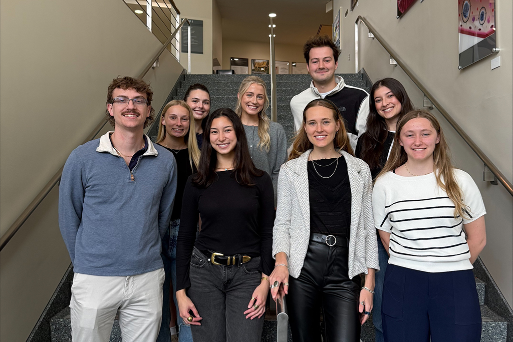 A group of PharmD students pose on the stairs in the School's atrium