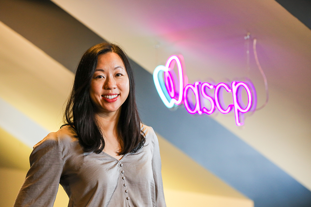 Jing Wu in front of a neon ASCP sign