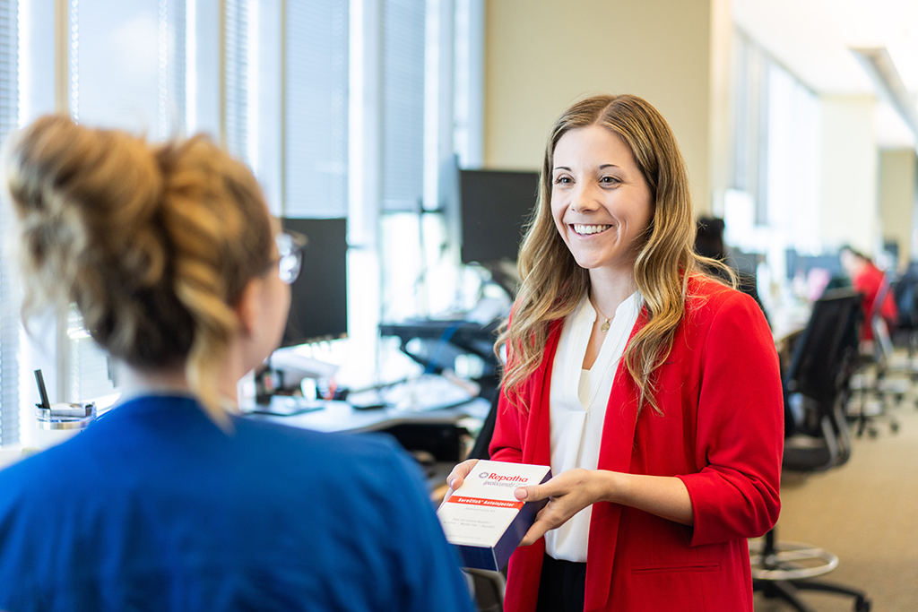Jordyn Salzgeber explains a medication to a woman facing away from the camera