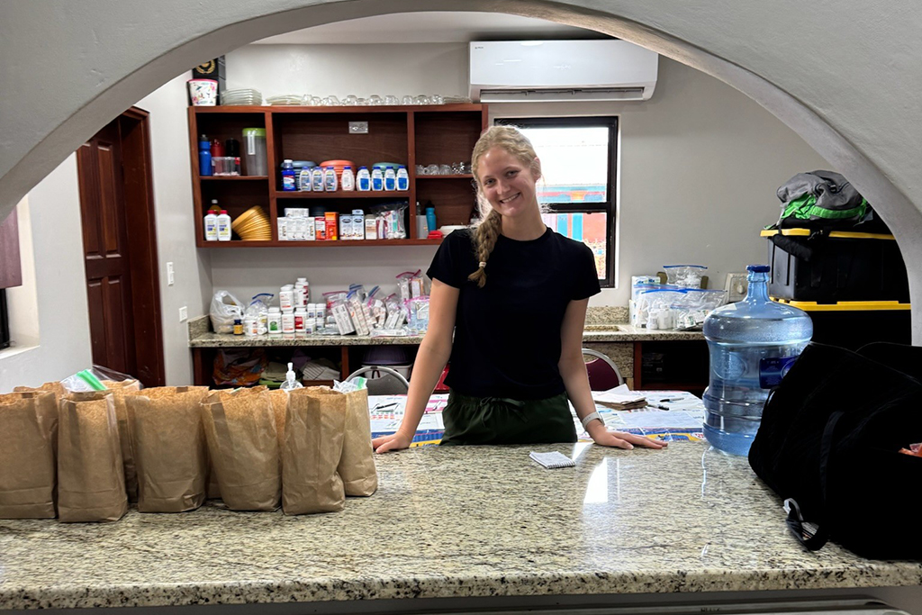 Katherine Kitslaar stands behind a counter that holds many paper bags