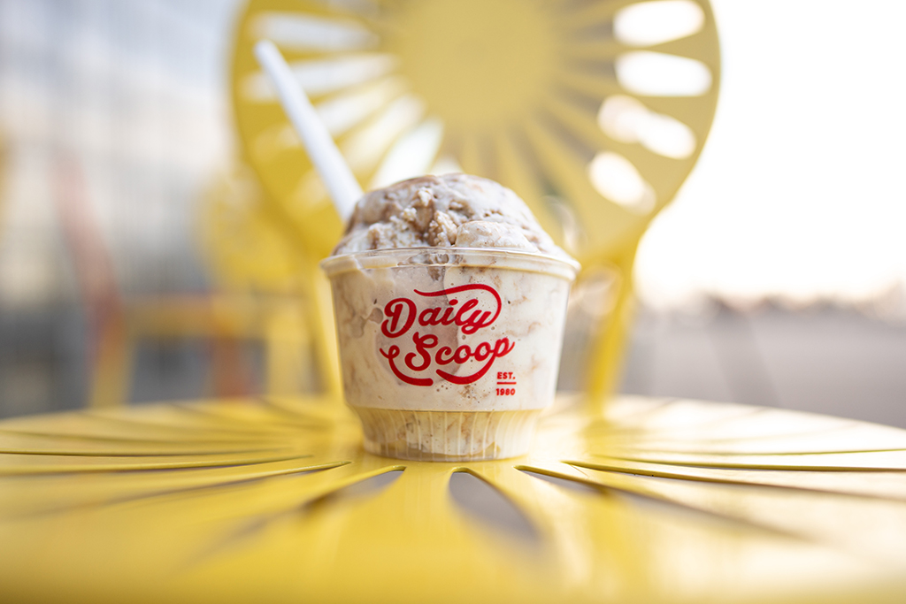Ice cream in a cup with the words "Daily Scoop" sitting on a yellow starburst chair at the Memorial Union Terrace