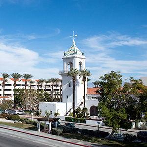 A photo of a white building, blue skies, and palm trees