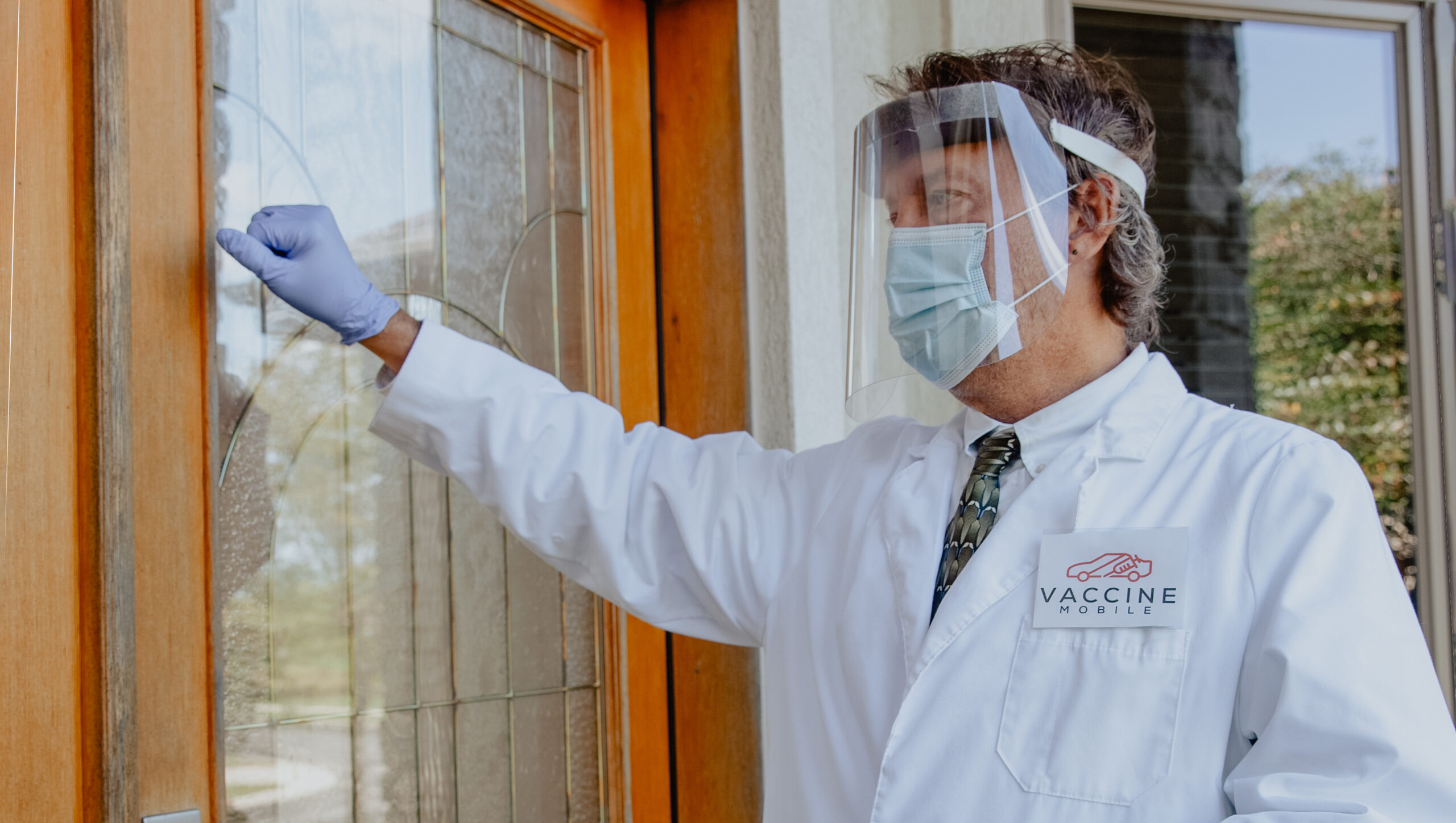 Lance Moran, dressed in PPE, knocking on a patient's door.