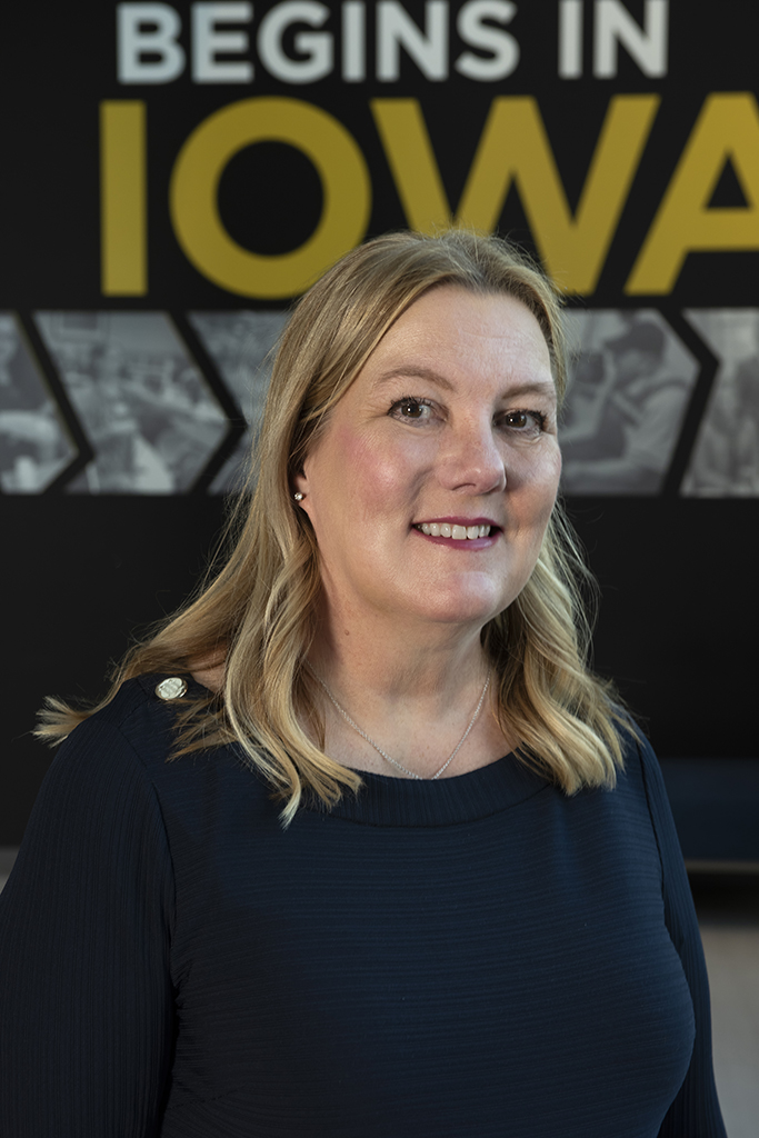 Jill Kolesar poses in front of an Iowa banner