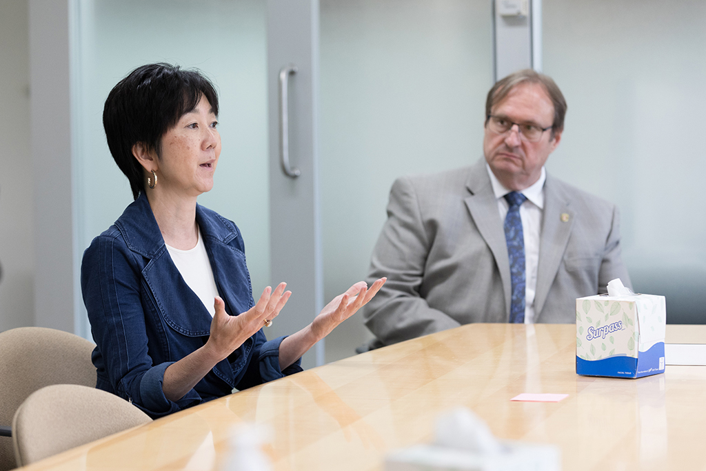 Michelle Chui speaks at a table with Dean Steve Swanson next to her.