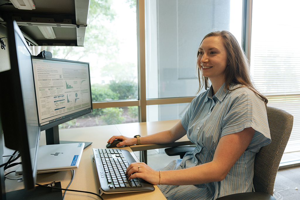 Miranda Murray types at her computer near a large window