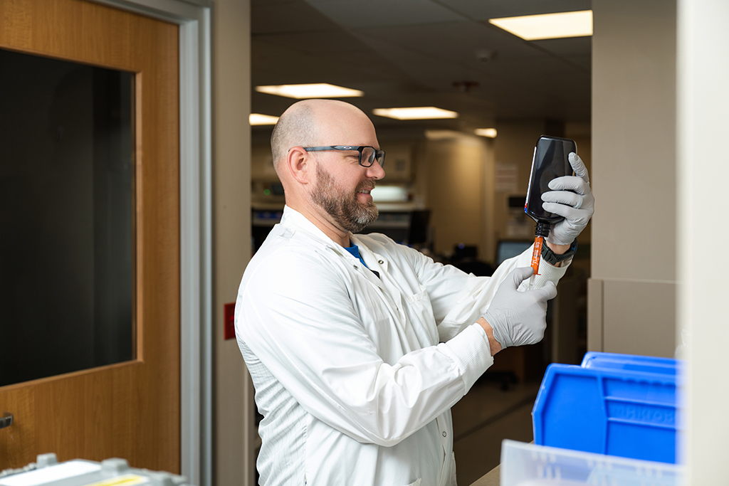 Nate Woolever fills a syringe from a brown bottle