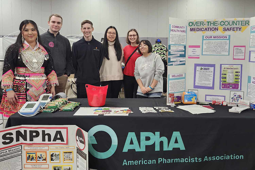 PharmD students behind a black APhA table with a tri-fold poster reading Over-the-Counter Medication Safety