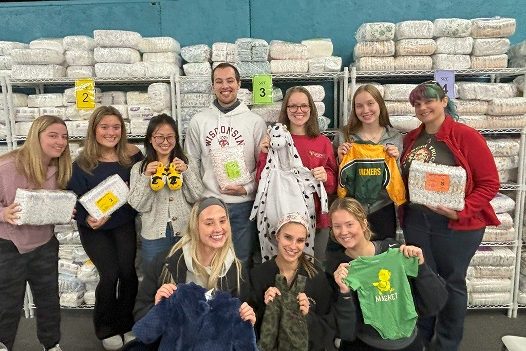 A group of PharmD students holding baby supplies, including diapers and onesies. 