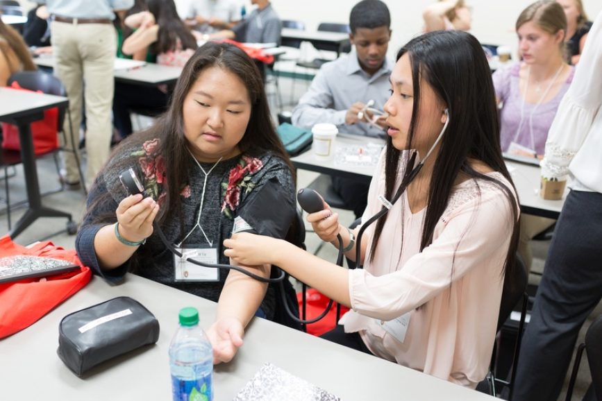 Two Pharmacy Summer Program students practice taking one another's blood pressure