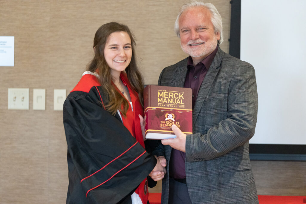 A PharmTox graduate and Jeff Johnson pose with the Merck Manual.