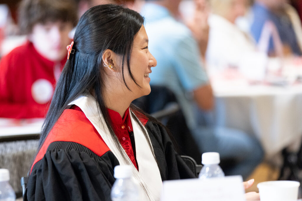 A PharmTox graduate smiles while seated at a table.
