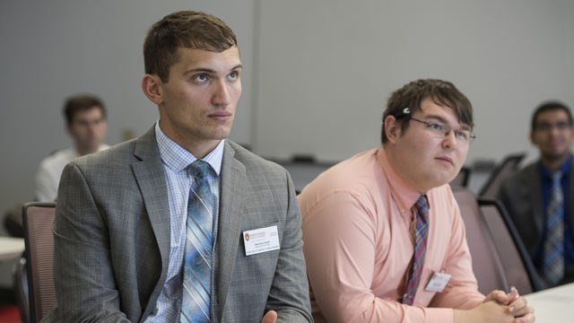 Herolind Jusufi and Michael Heltne sitting at a table watching the speaker