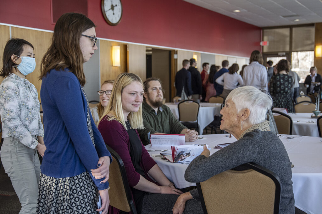 PharmD student Marissa Hakala (standing) listens with classmate Stacy Soltis (seated) as her great Aunt Liz Allen talks to them during the 2022 School of Pharmacy Scholarship Brunch