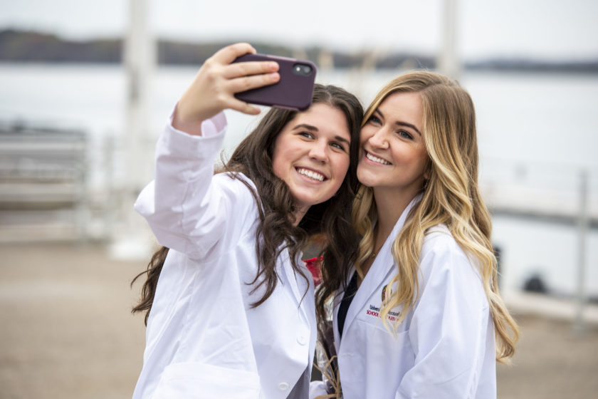 Two students in white coats taking a selfie after white coat ceremony