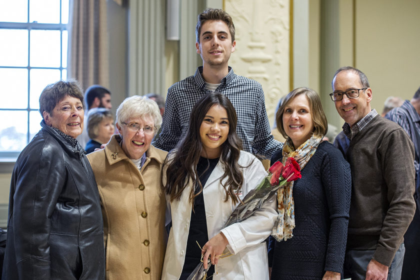 Student in white coat with their family after white coat ceremony