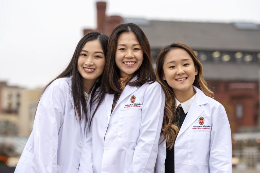 Three students in white coats standing together after white coat ceremony