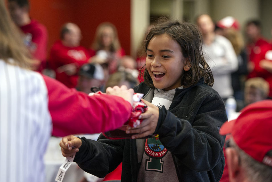 A young child accepting a raffle prize at the UW-Madison Pharmacy Alumni Tailgate event, held at Union South during the Badgers vs. Cornhuskers game.