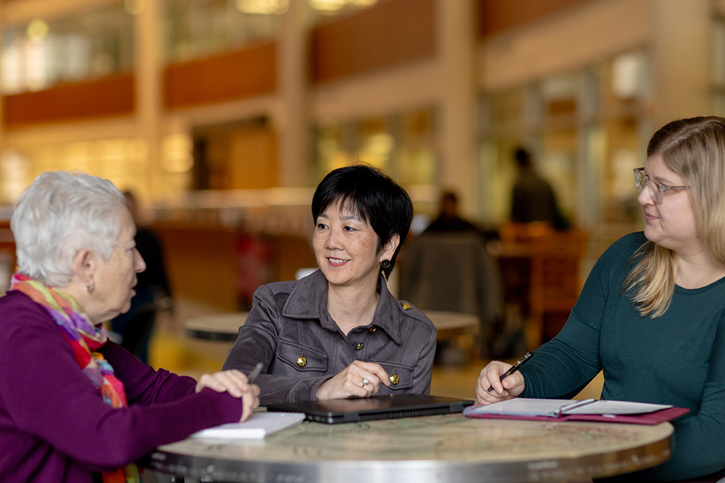 Michelle Chui sitting at a table speaking with two women