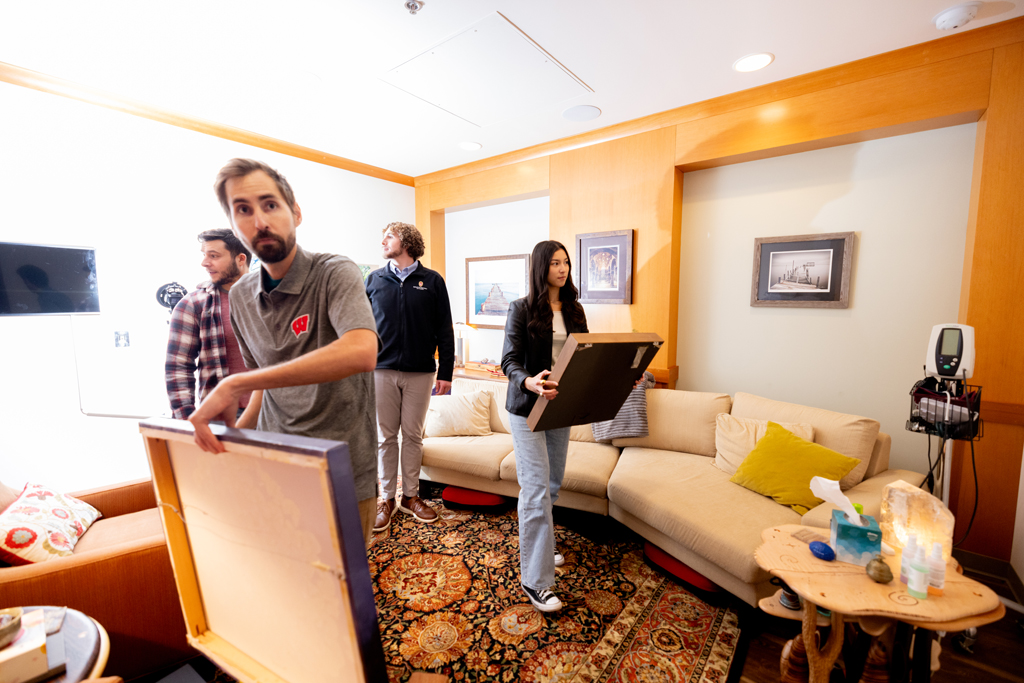 Wenthur and his team (left to right in the background: Nate Jones, a graduate student in the Molecular and Cellular Pharmacology PhD Program, and PharmD students Blake O’Connor and Sophia Castillo) consider where to hang new art in the psychedelic-assisted therapy room.