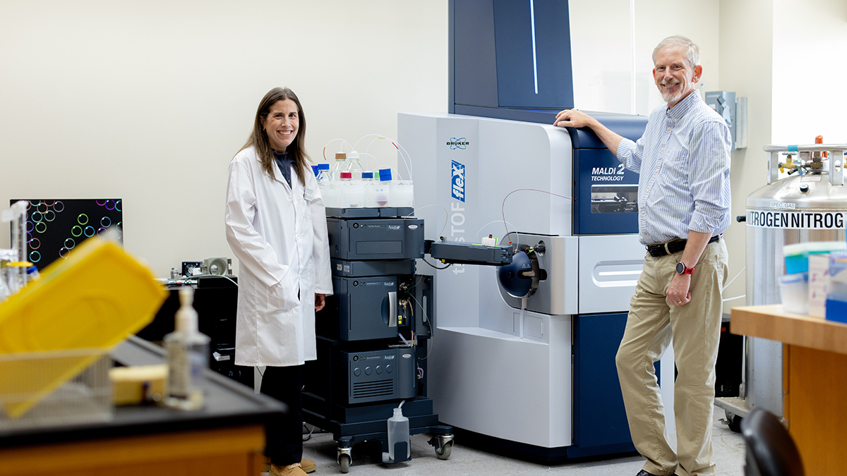 Molly Pellitteri Hahn and Cameron Scarlett stand near mass spectrometry equipment