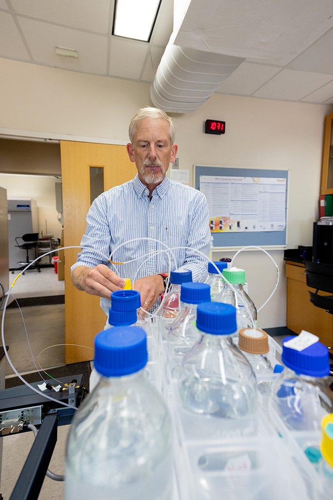 Cameron Scarlett adjusting tubing coming out of bottles with blue caps
