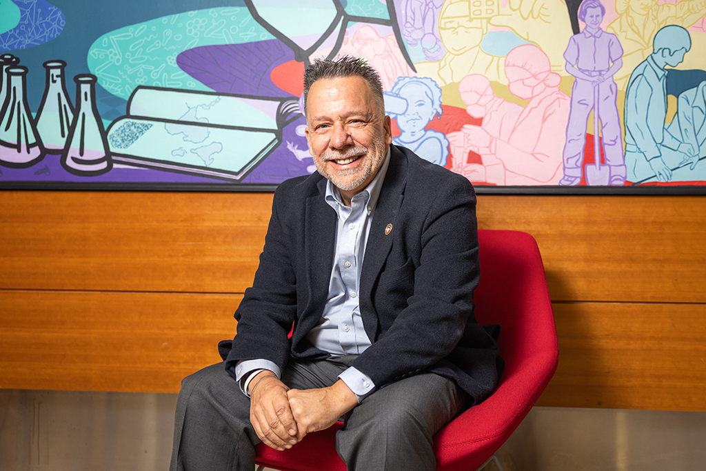 An environmental portrait of Greg Primuth in front of a colorful mural