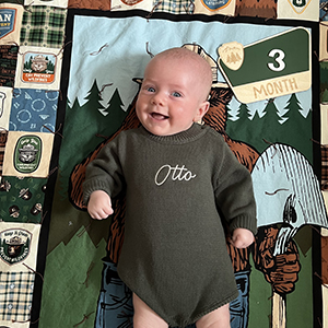 A baby in a green sweater that says 'otto'