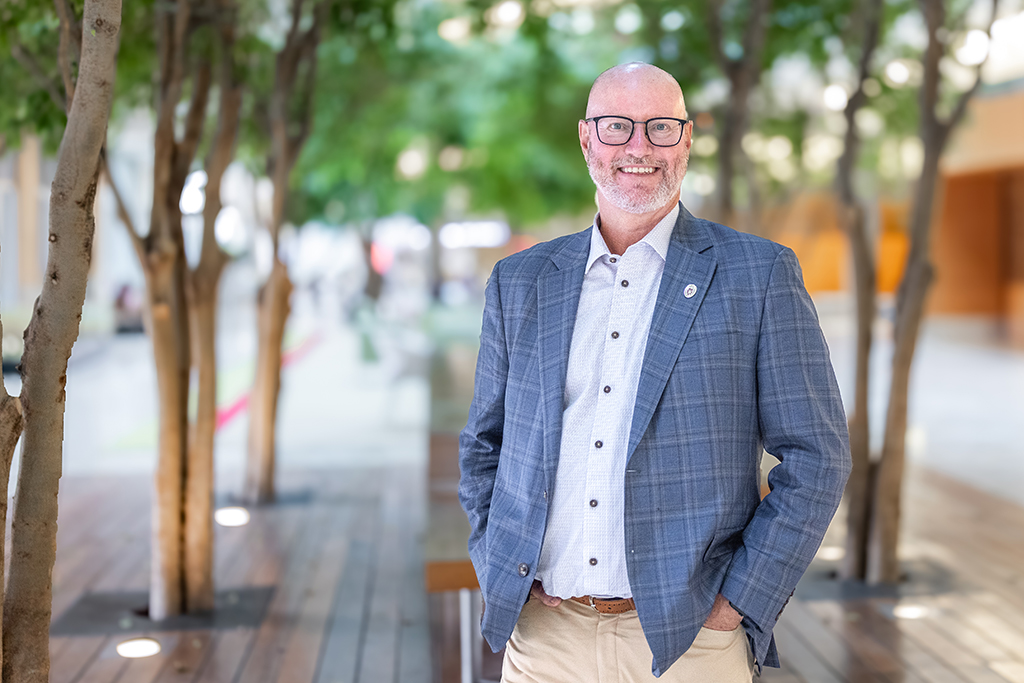 Environmental portrait of Steve Rough in front of trees in an atrium