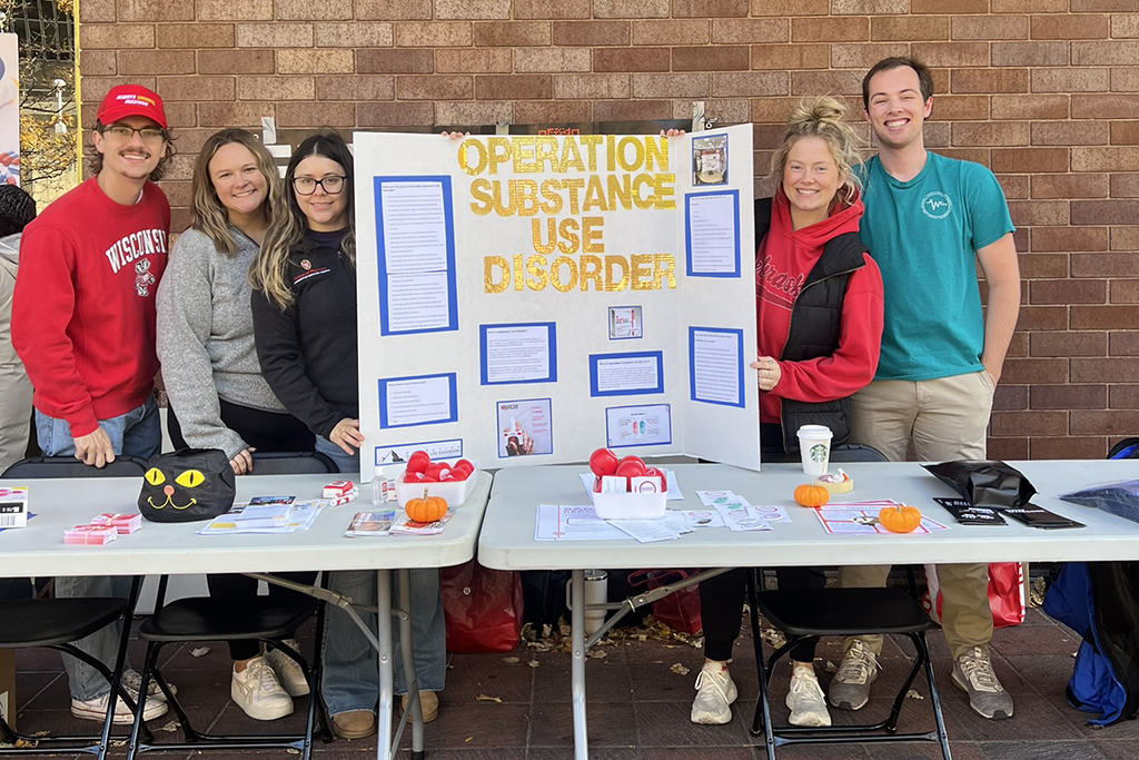 Students around a tri-fold poster about Operation Substance Use Disorder