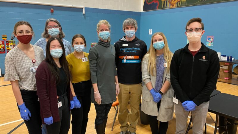 School of pharmacy volunteers standing with masks and gloves in the Boys & Girls Taft Club small gym