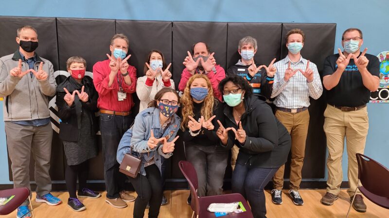 School of pharmacy volunteers wearing masks in a group photo and forming a "W" with their hands