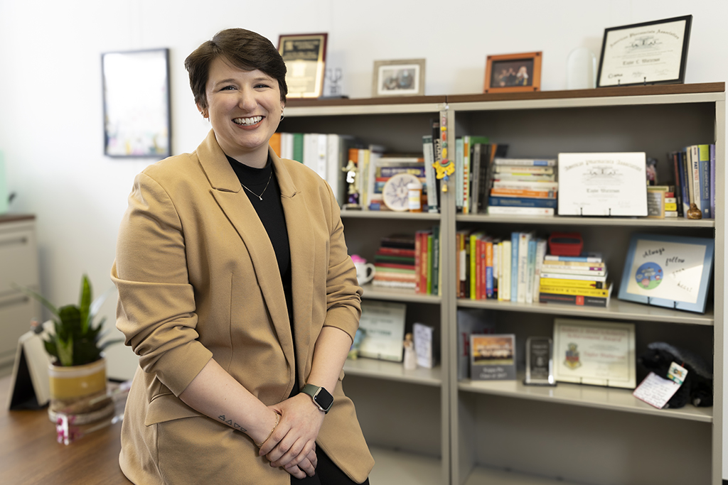 Taylor Watterson portrait in front of a shelf of books and framed documents