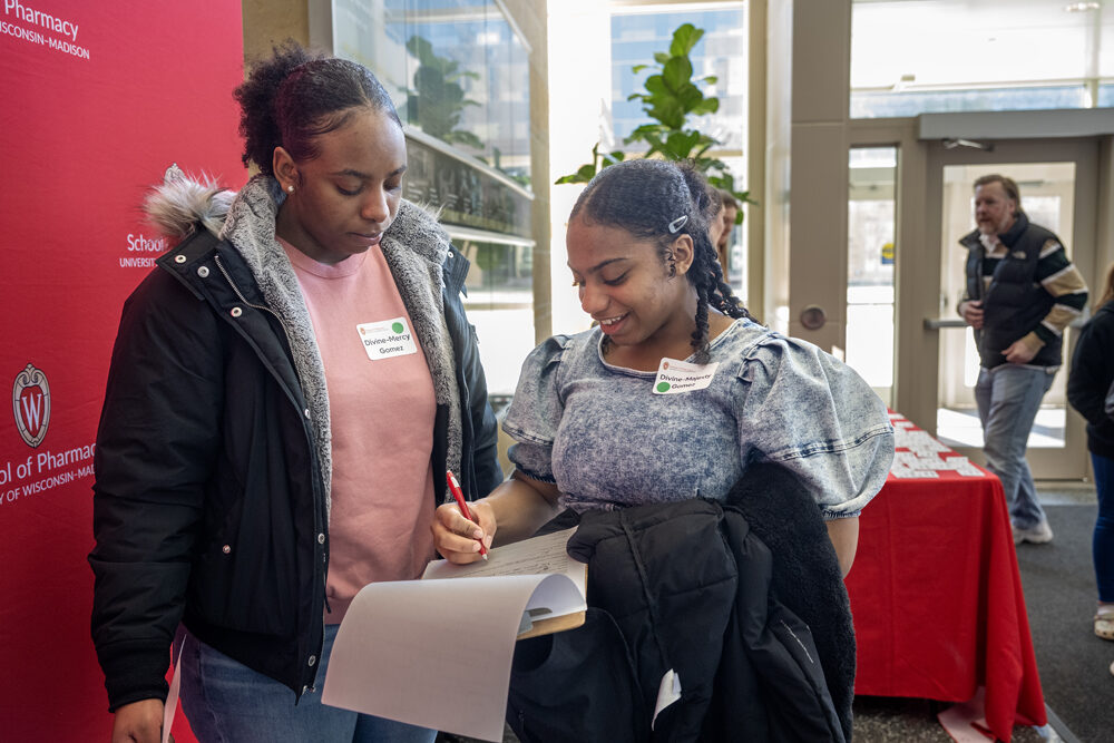 Mercy Gomez looks on as her sister Majesty fills out a form before the Wonders of Pharmacy on Saturday, March 2, 2024, at the School of Pharmacy on the campus of UW-Madison. (Photo Paul L. Newby, II)