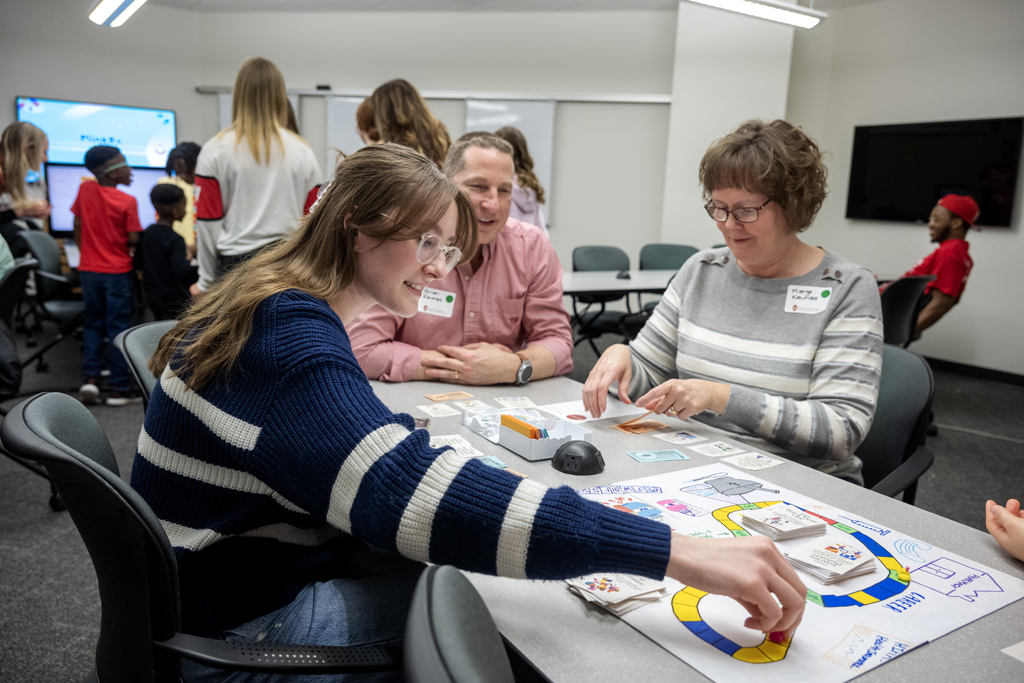 While her parents, Marge and Brian, look on, Sarah Kaunas moves her game piece around the board as she plays the Woph Game of Life during the Wonders of Pharmacy on Saturday, March 2, 2024, at the School of Pharmacy on the campus of UW-Madison. (Photo Paul L. Newby, II)