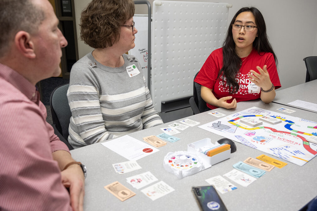 PharmD student Sydney Thao explains the object of the game to Sarah Kaunas' parents, Marge and Brian Kaunas, as they play the Woph Game of Life during the Wonders of Pharmacy on Saturday, March 2, 2024, at the School of Pharmacy on the campus of UW-Madison. (Photo Paul L. Newby, II)