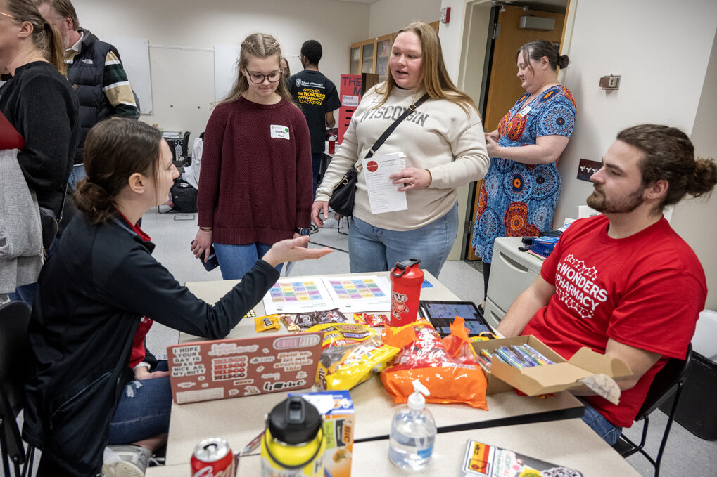 First-year PharmD students Megan Johnson and Elliot Quinn explain to Sophia Van and her mother, Courtney Van, how to play Pill Pursuit Bingo during the Wonders of Pharmacy on Saturday, March 2, 2024, at the School of Pharmacy on the campus of UW-Madison. (Photo Paul L. Newby, II)