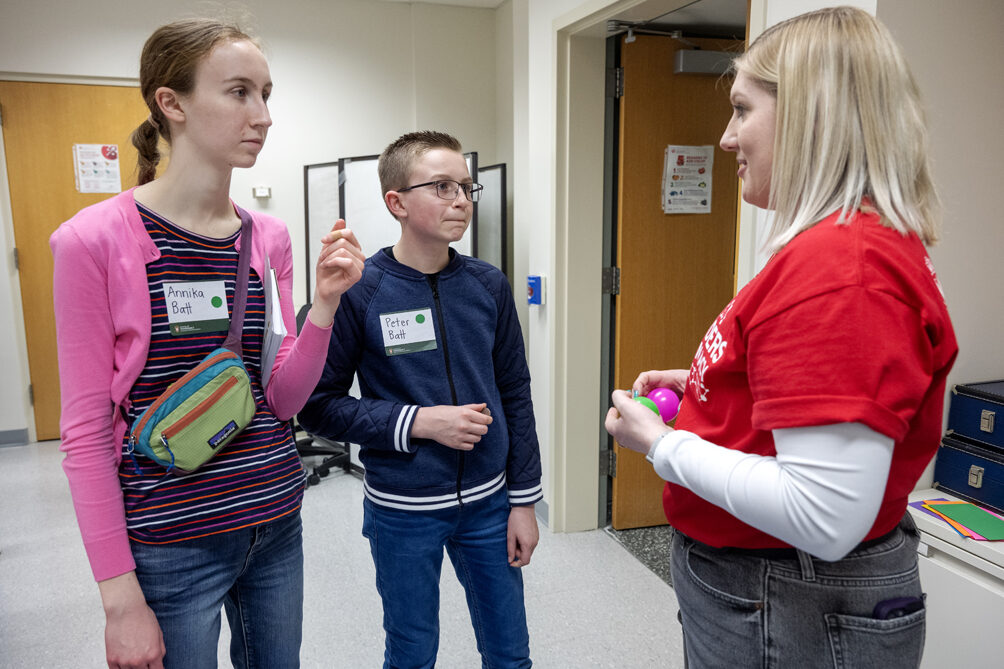 First-year PharmD student Lexi Wery explains the rules to Annika Batt and her brother, Peter Batt, as they prepare to play the Pharmacy Pipeline activity during the Wonders of Pharmacy on Saturday, March 2, 2024, at the School of Pharmacy on the campus of UW-Madison. (Photo Paul L. Newby, II)