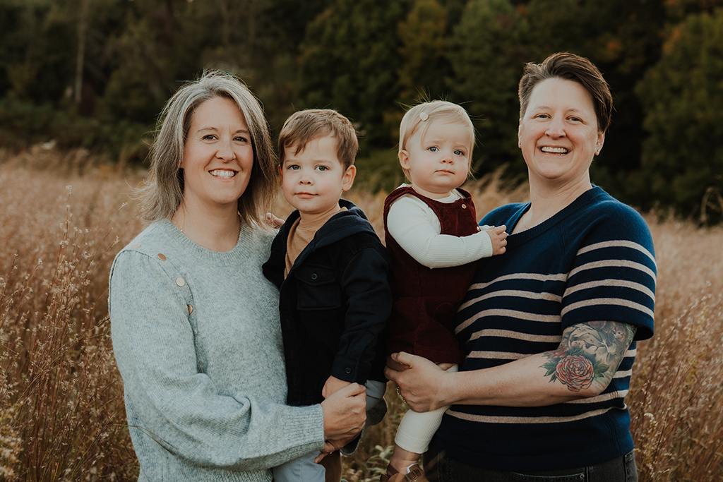 Patricia Thornewell and her wife hold their two children in a field