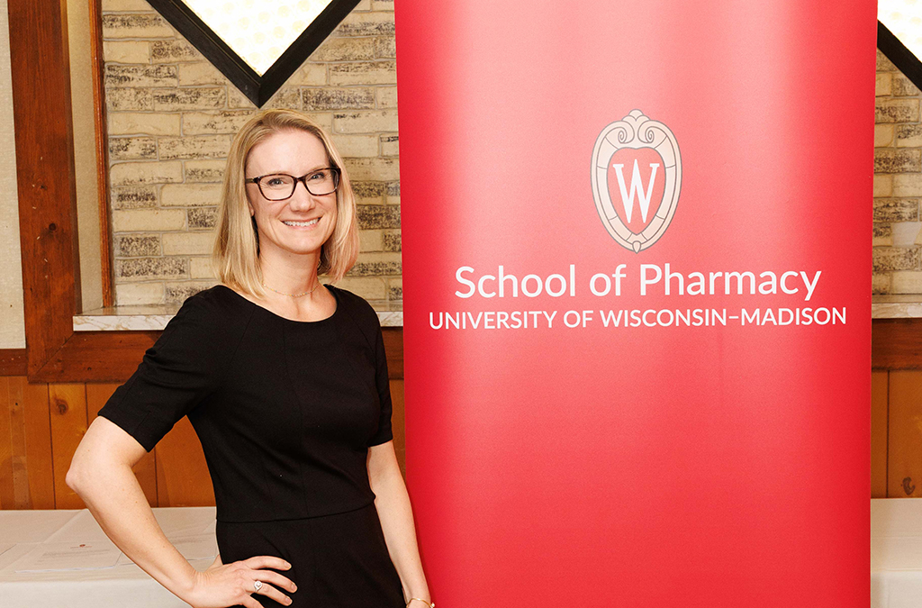 Erika Smith poses next to a red School of Pharmacy banner