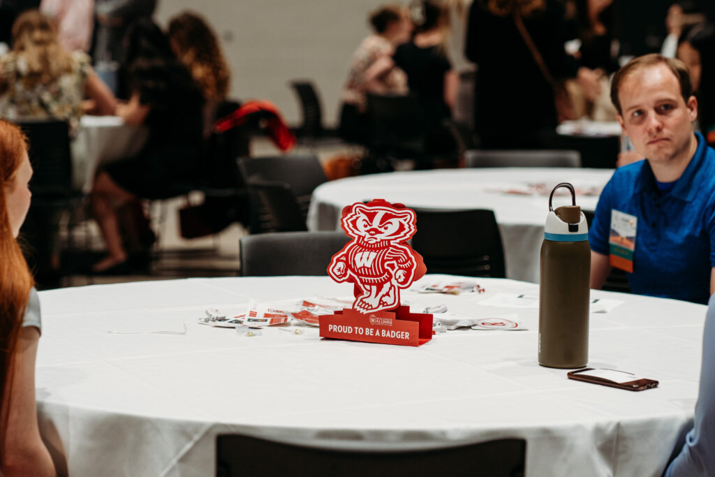 An alum seated at a table with a "Proud to be a Badger" centerpiece.