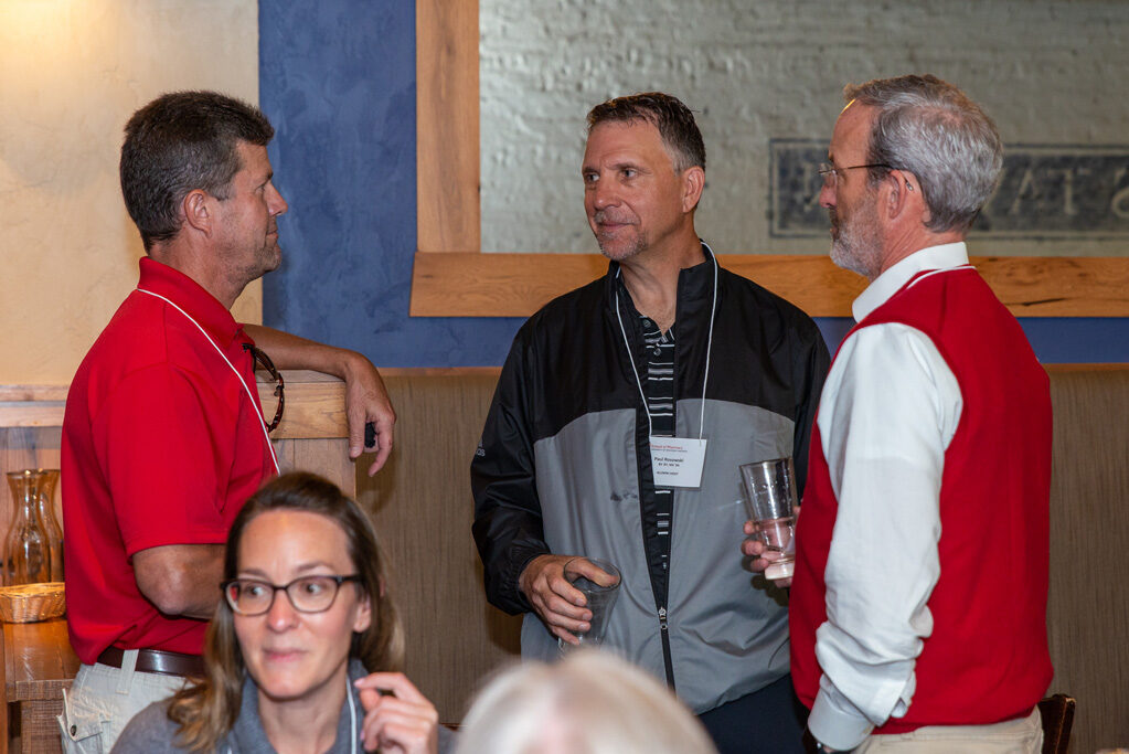 Dave Mott speaking with other staff and alumni at Cooper's Tavern